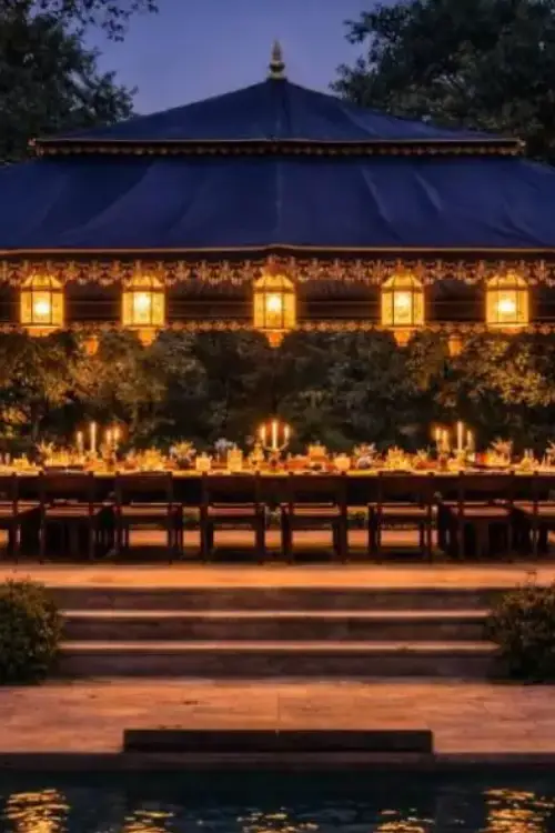 Sawai Villas Evening outdoor banquet under a blue-roof pavilion with illuminated lanterns lining a long candlelit table beneath trees.