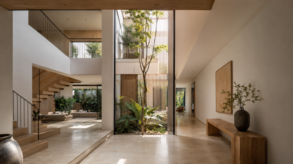 Open living hall with central indoor garden, wooden staircase, and minimalist seating.
